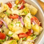 artichoke salad in a white bowl topped with chopped basil.