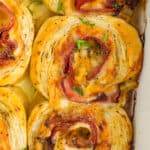 6 ham and cheese pinwheels in a white baking dish.