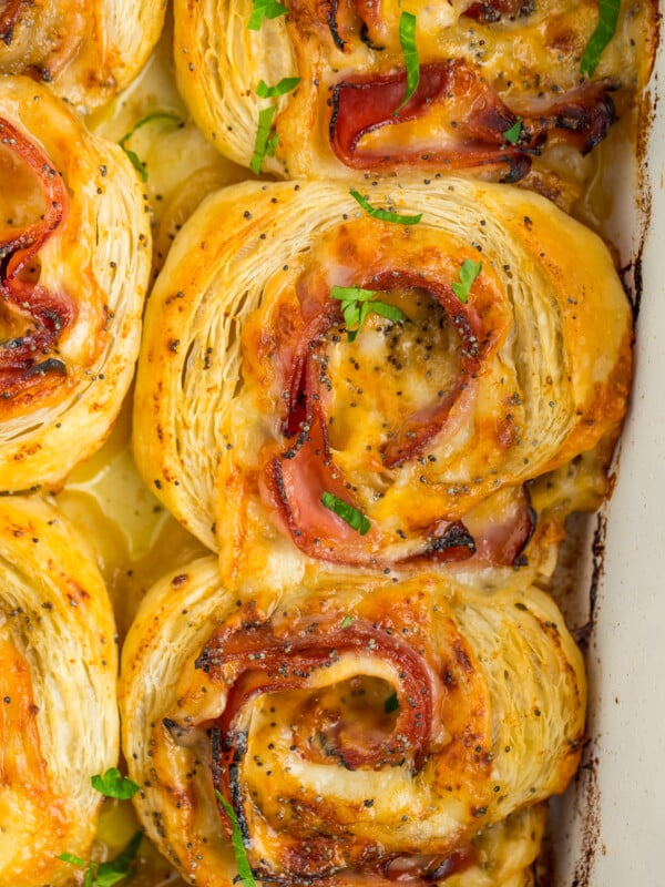 6 ham and cheese pinwheels in a white baking dish.