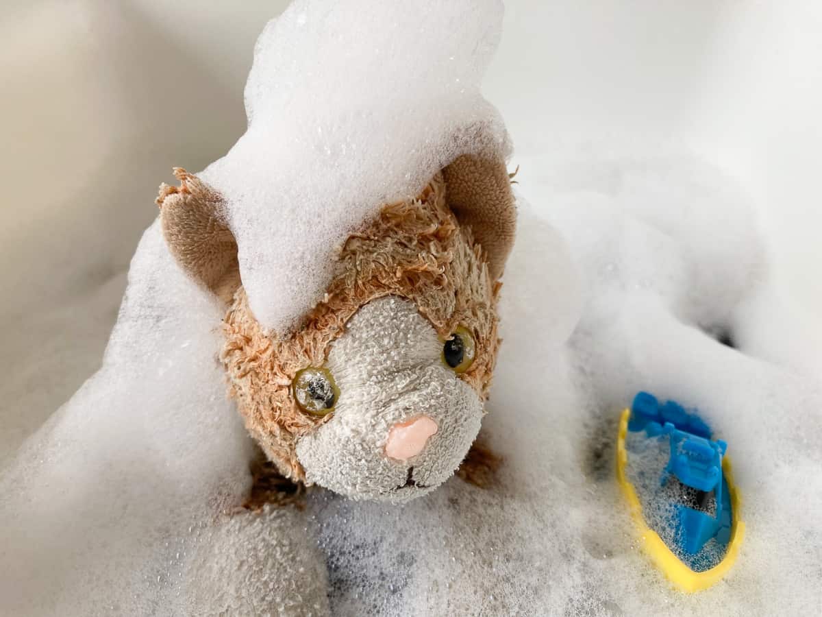 a stuffed cat in a bubble bath with a bath toy.