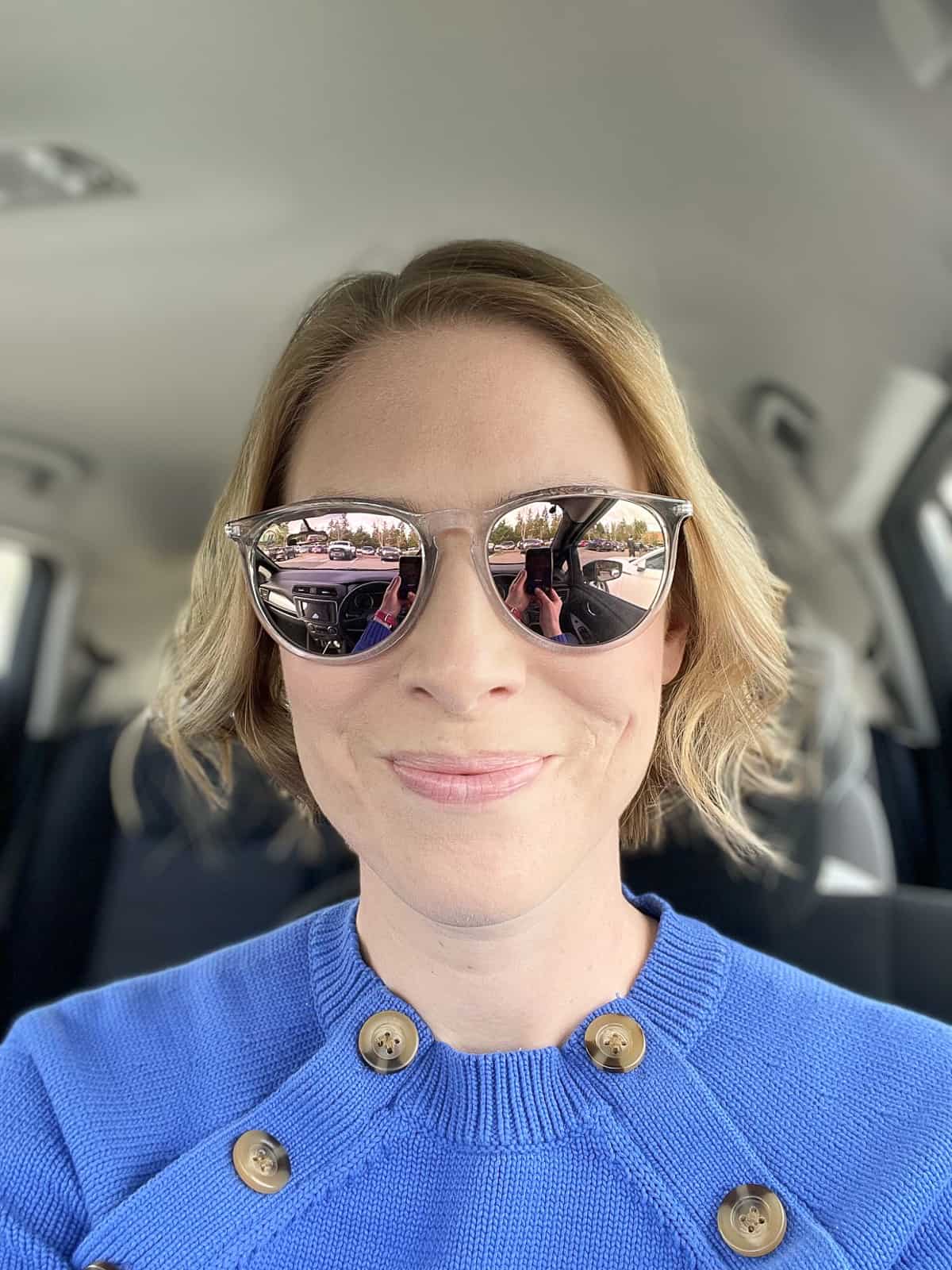 a woman in a blue sweater wearing sunglasses