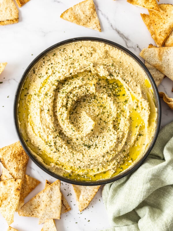 homemade hummus in a black bowl topped with seeds and olive oil.