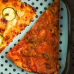 2 slices of leftover pizza in an air fryer with a blue air fryer liner.