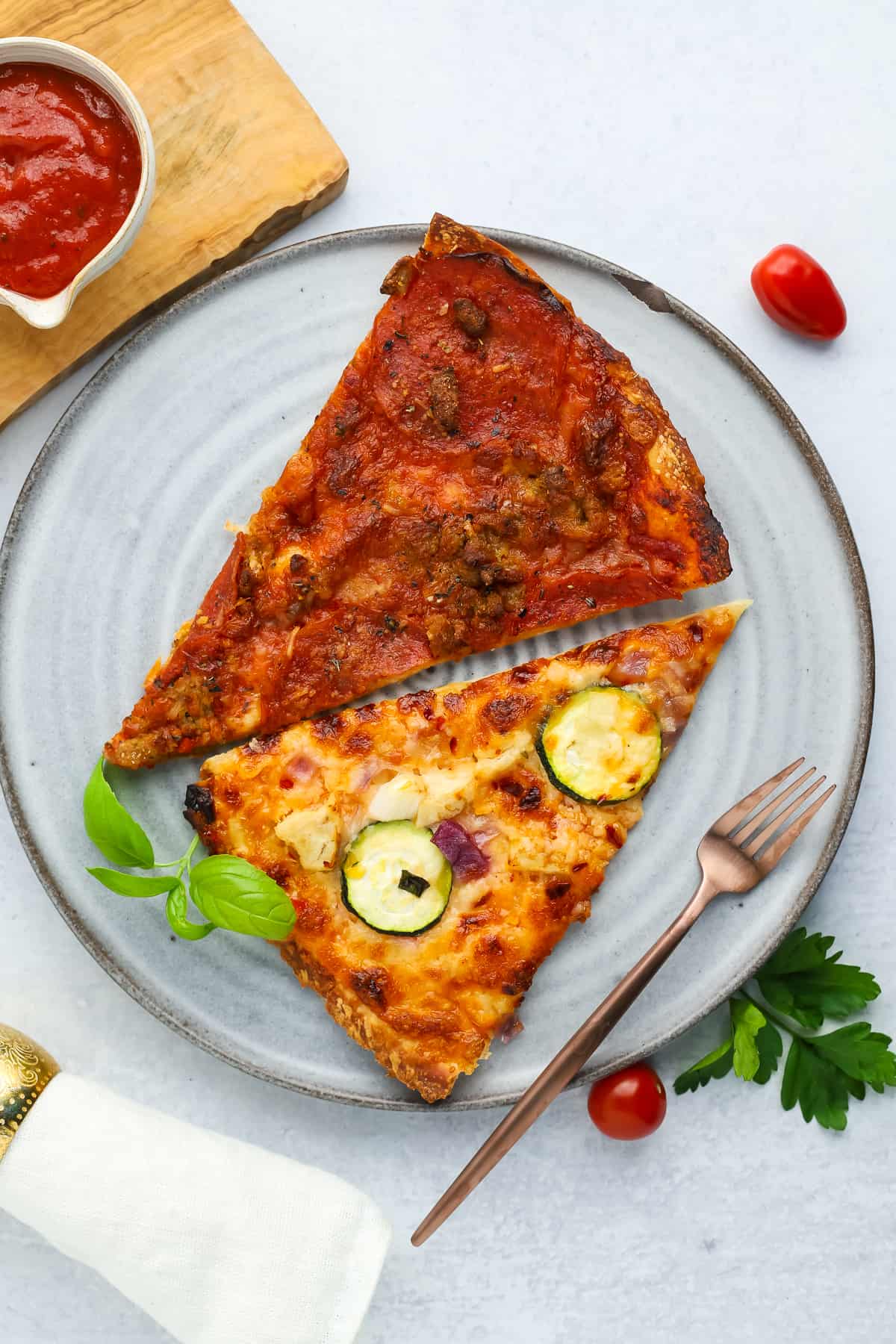 2 slices of pizza on a grey plate with a bronze fork.