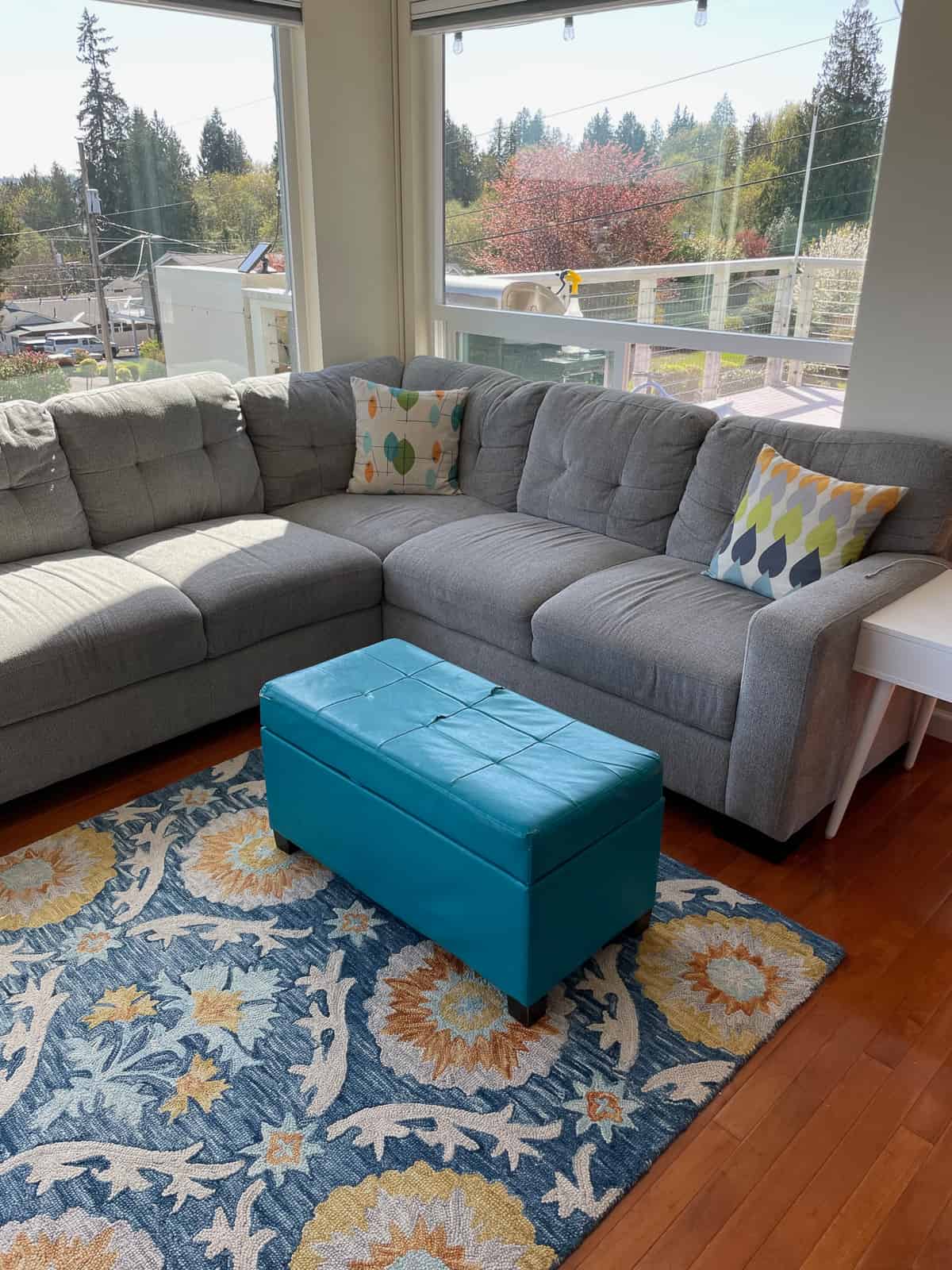 a living room with a teal footstool.