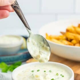a spoon hovering over a bowl of tartar sauce.