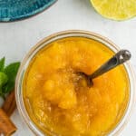 a glass dish of pineapple jam with a small bronze spoon in it.