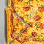 a puff pastry pizza with slices removed. The pizza is topped with pepperoni and shredded basil.