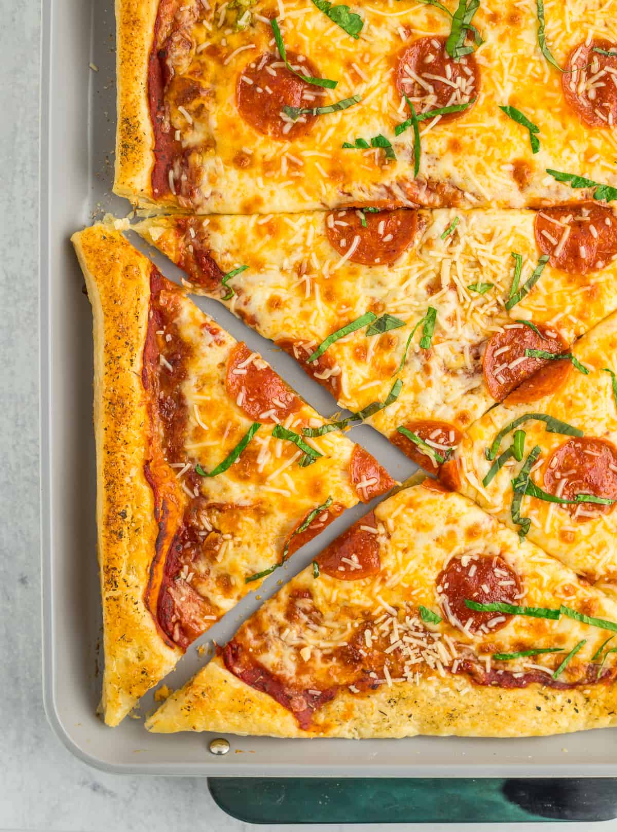 a puff pastry pizza with slices removed. The pizza is topped with pepperoni and shredded basil.