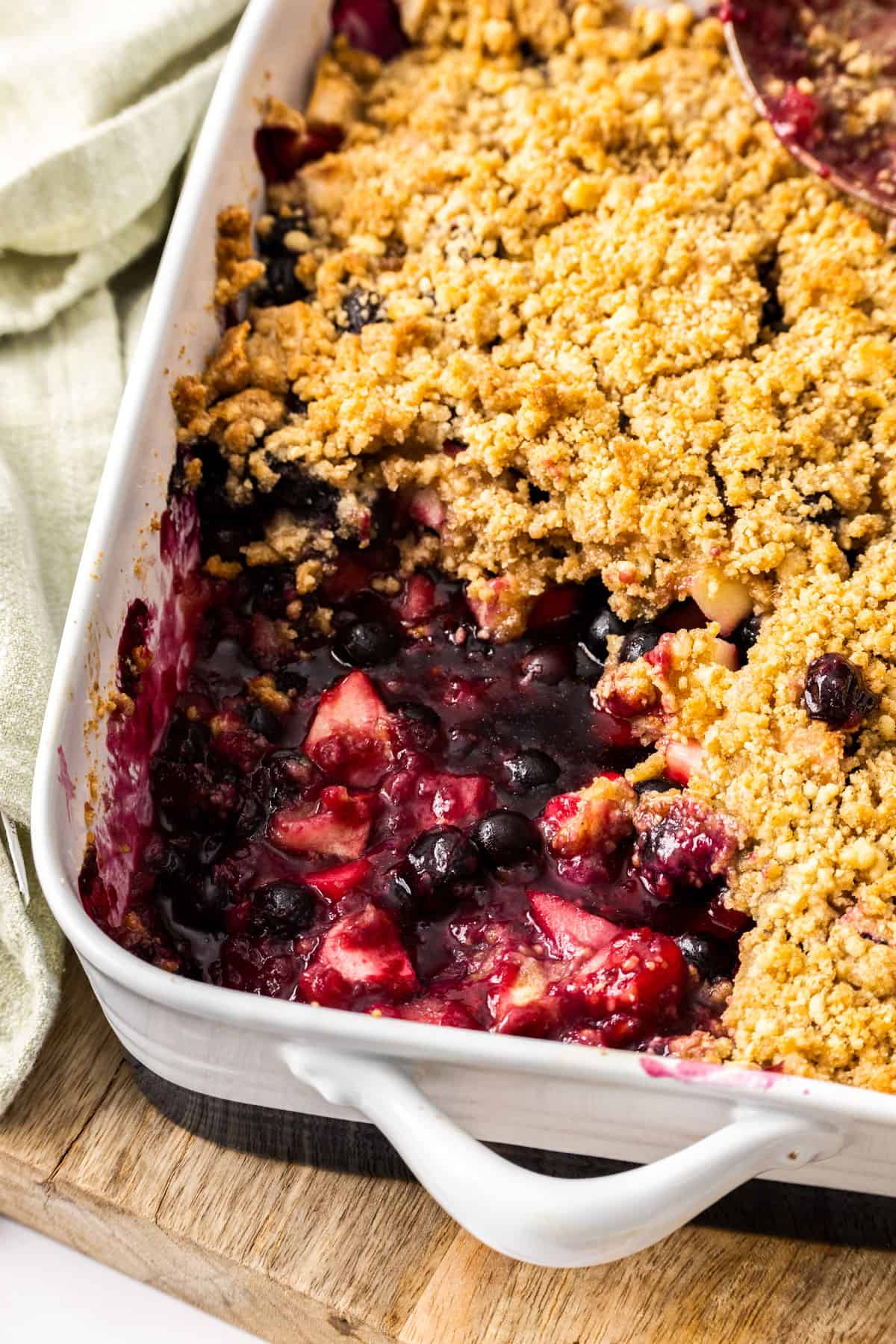 blueberry and apple crisp in a baking dish with a scoop missing.