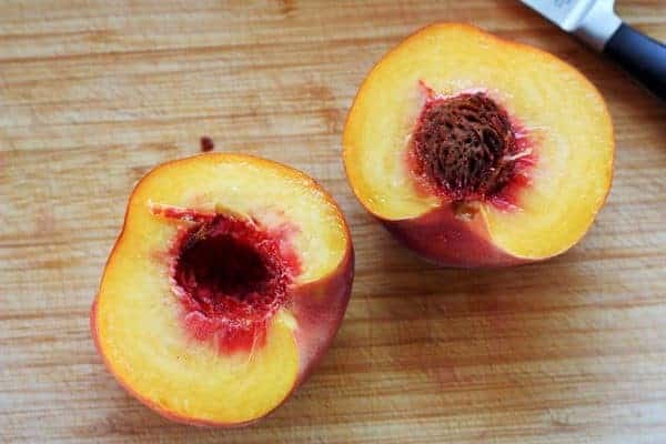 a peach cut in half with a pit.
