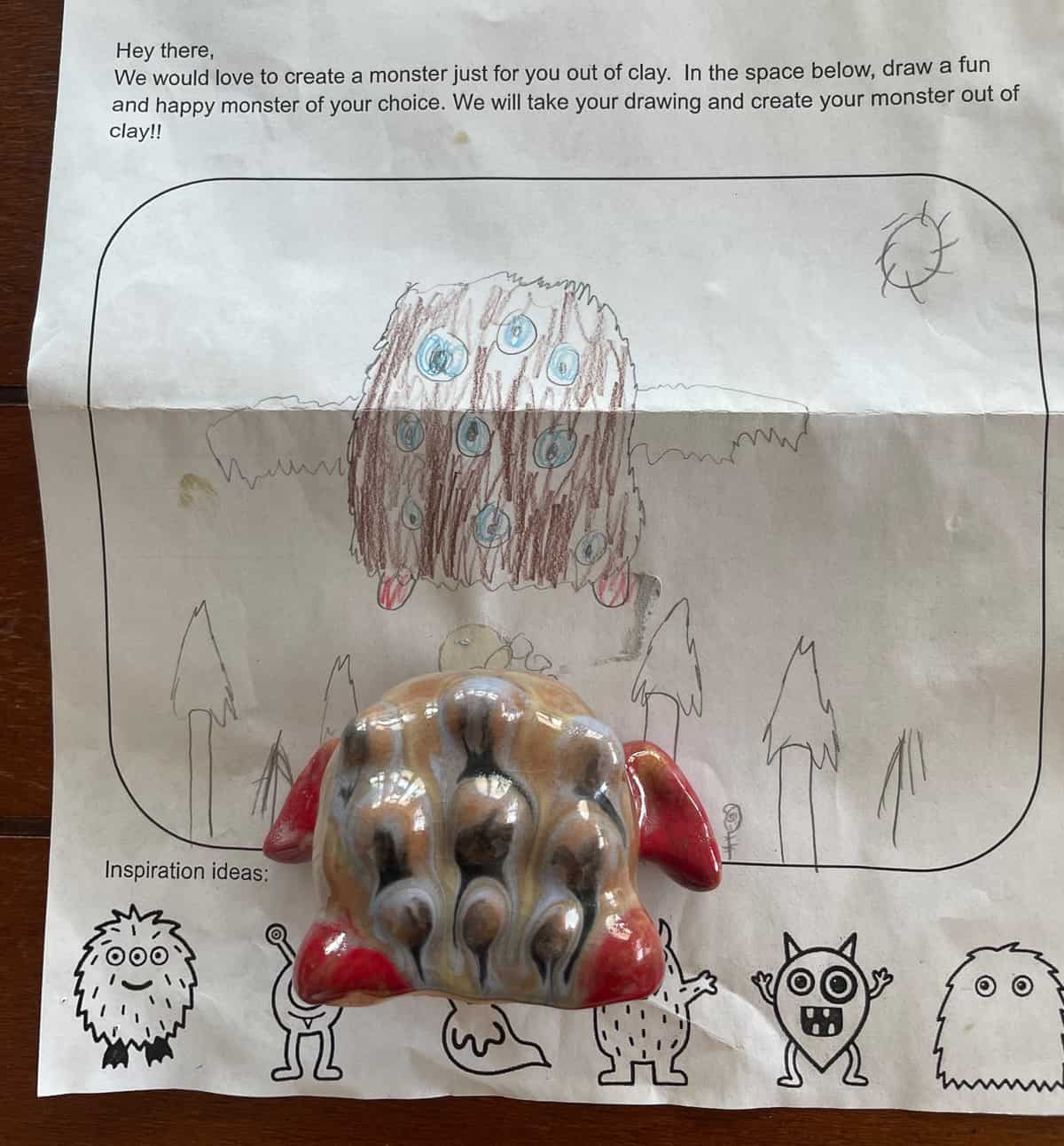 a ceramic monster in front of a monster colored on a piece of paper.