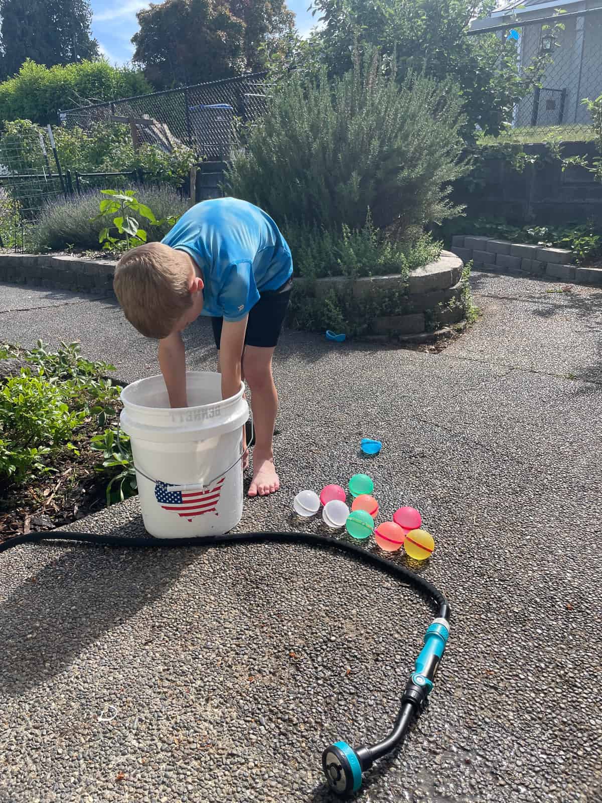 a kid playing in a bucket with reusable water balloons.