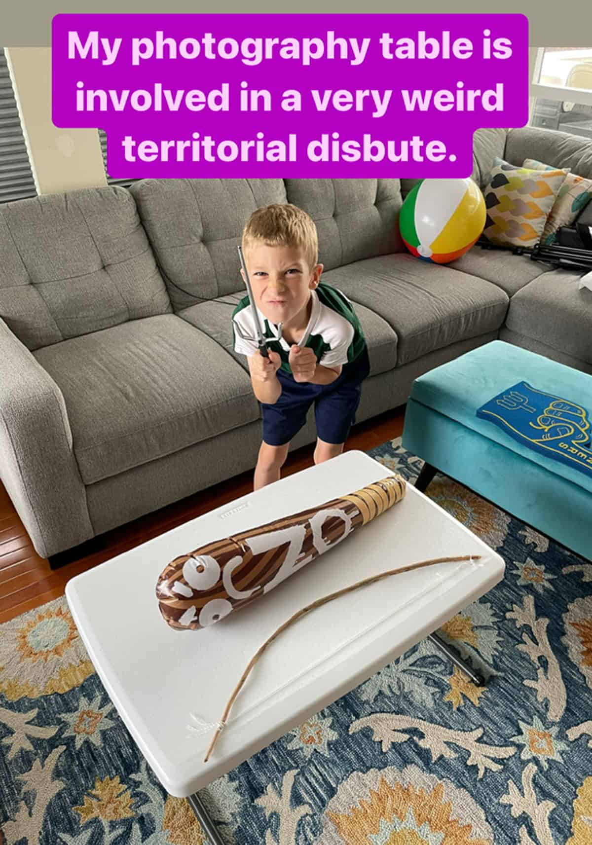a kid standing in a living room in front of a small folding table.