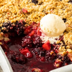 a dish of fruit crisp with a scoop of ice cream on top.