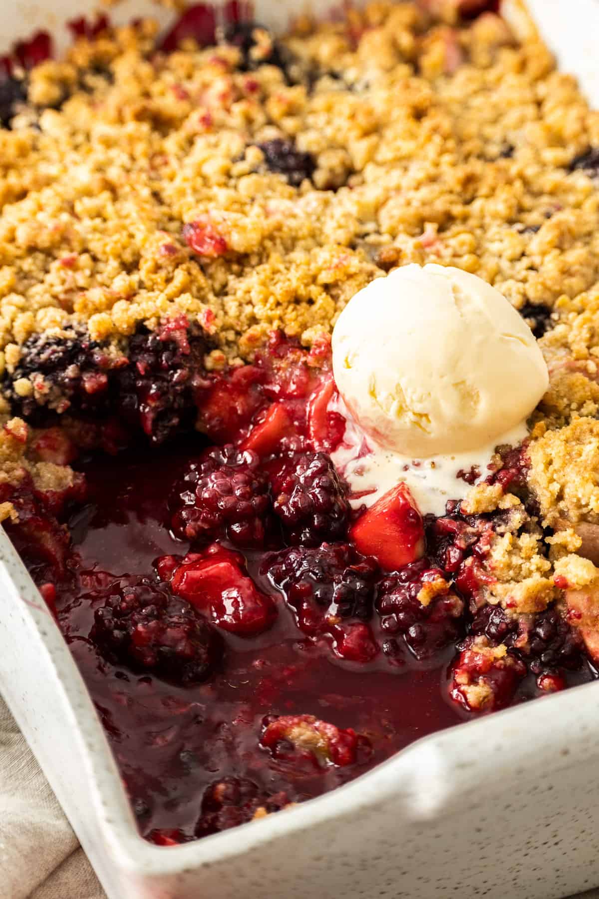 a dish of fruit crisp with a scoop of ice cream on top.