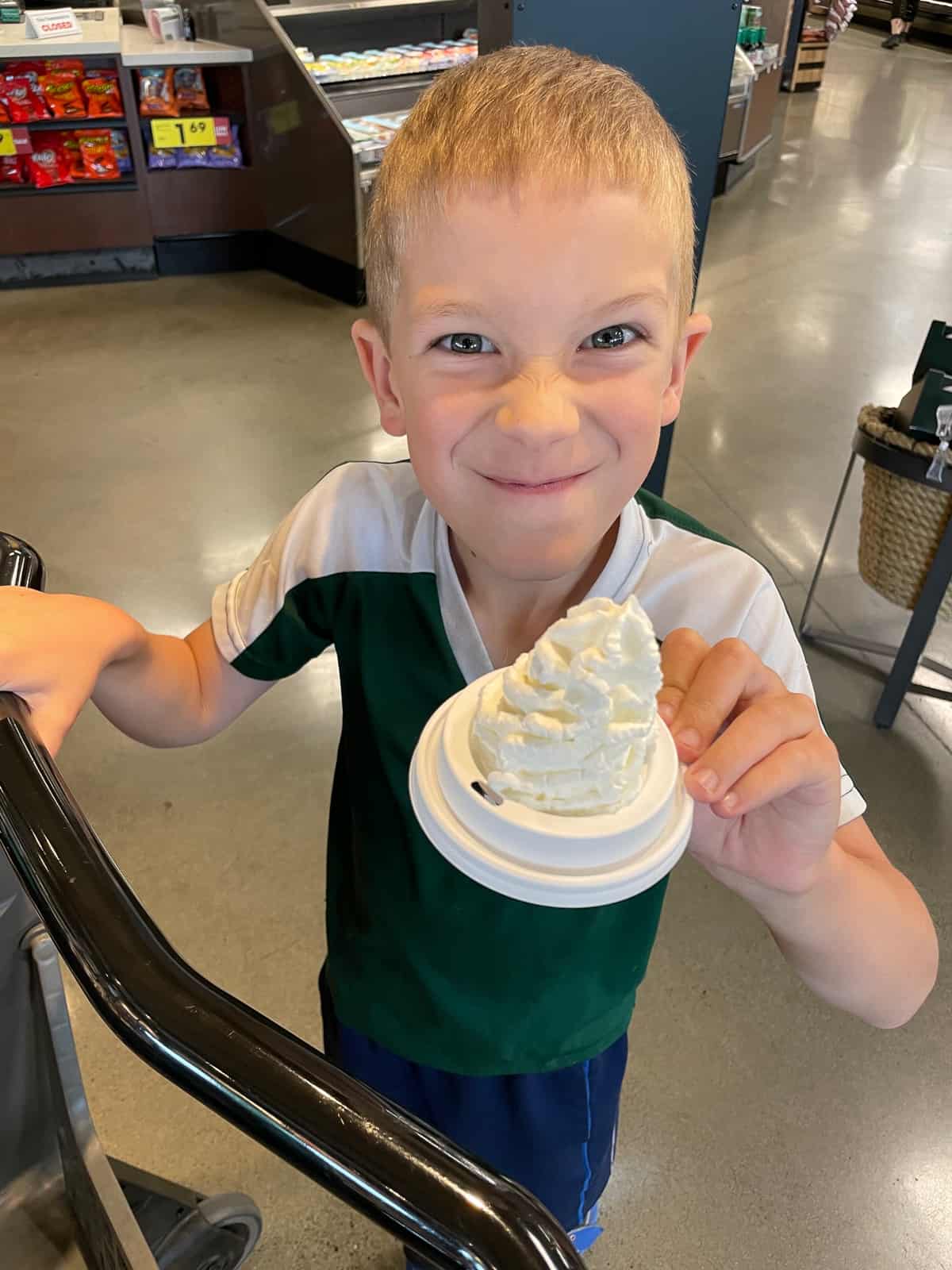a kid holding a lid of whipped cream.