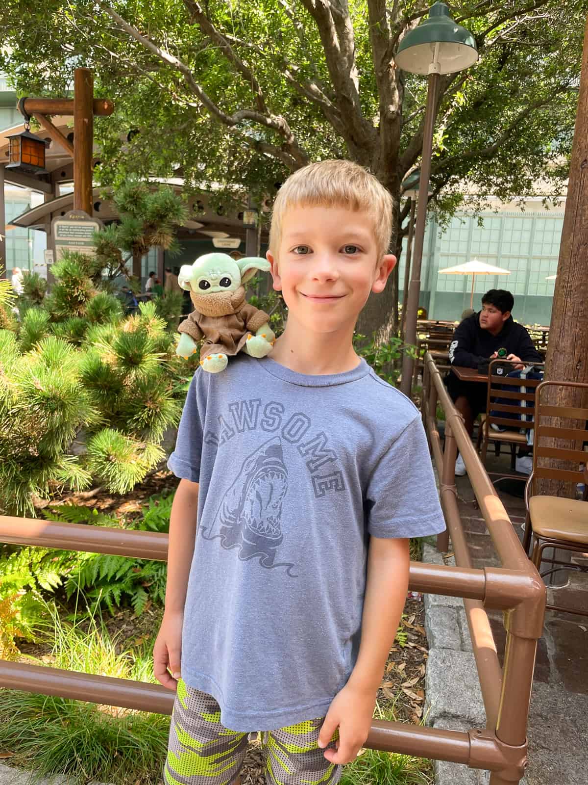 a little boy with a baby yoda shoulder buddy on his shirt.