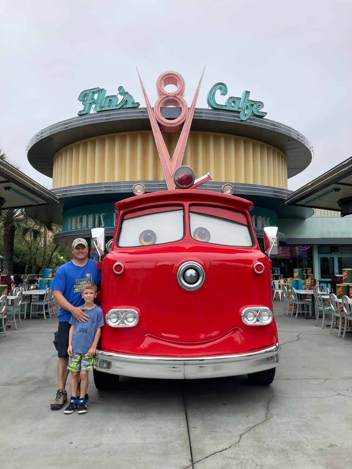 a father and son at Disneyland in front of the Cars fire truck.