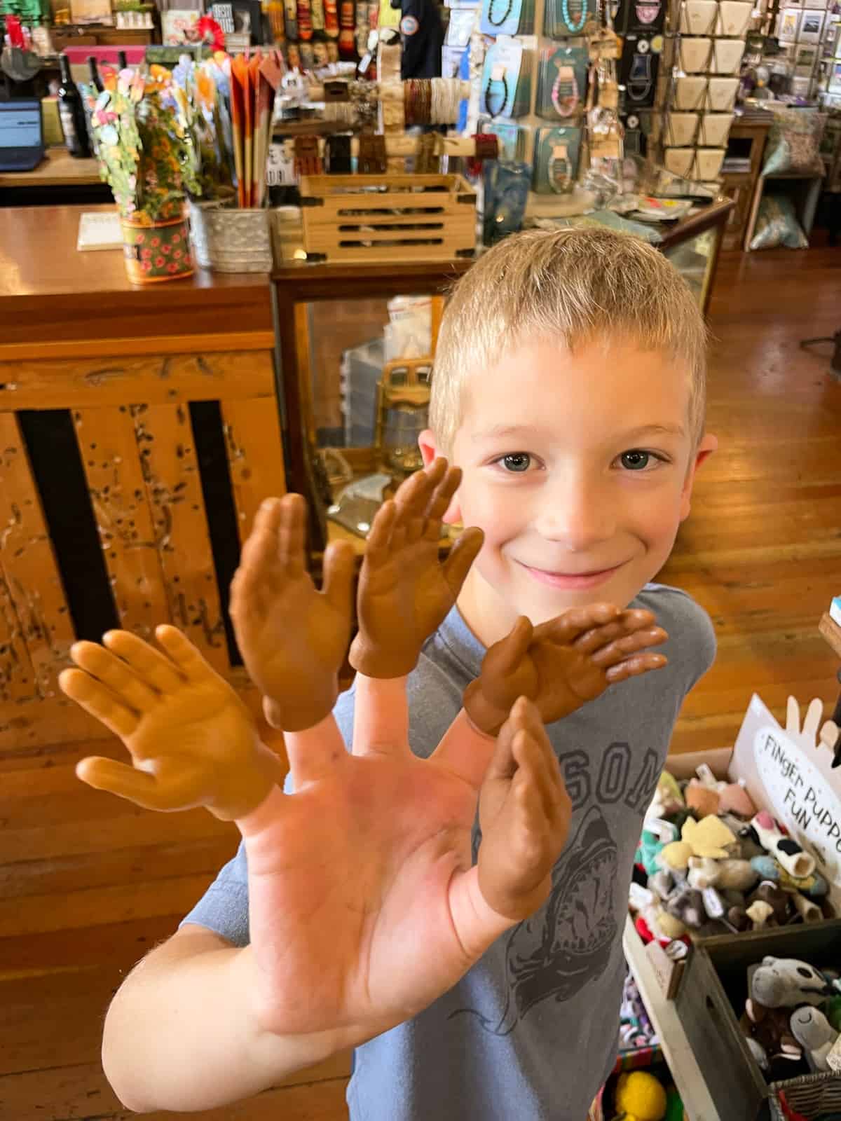 a kid with tiny finger puppets on his fingers.