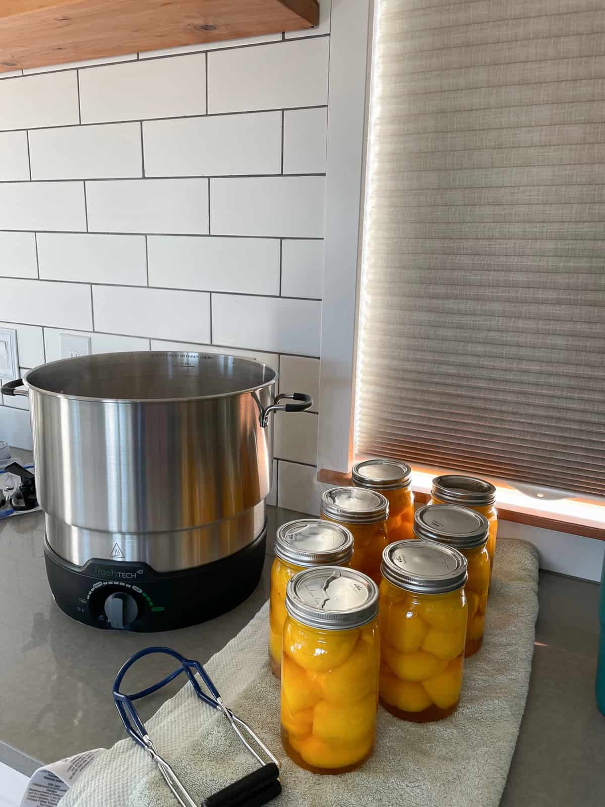 canned peaches on a towel on a countertop with a closed shade behind it.