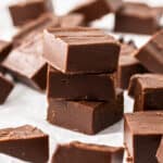 3 pieces of chocolate fudge stacked on top of each other, surrounded by other squares.