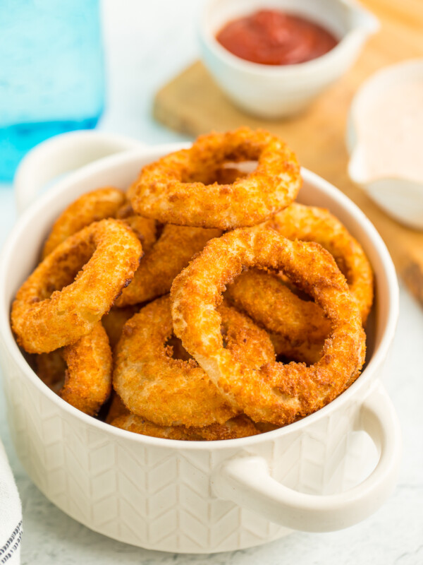 A white bowl stacked with air fryer onion rings.