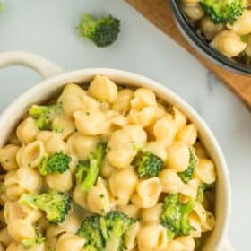 A white dish with cheese noodles and broccoli.