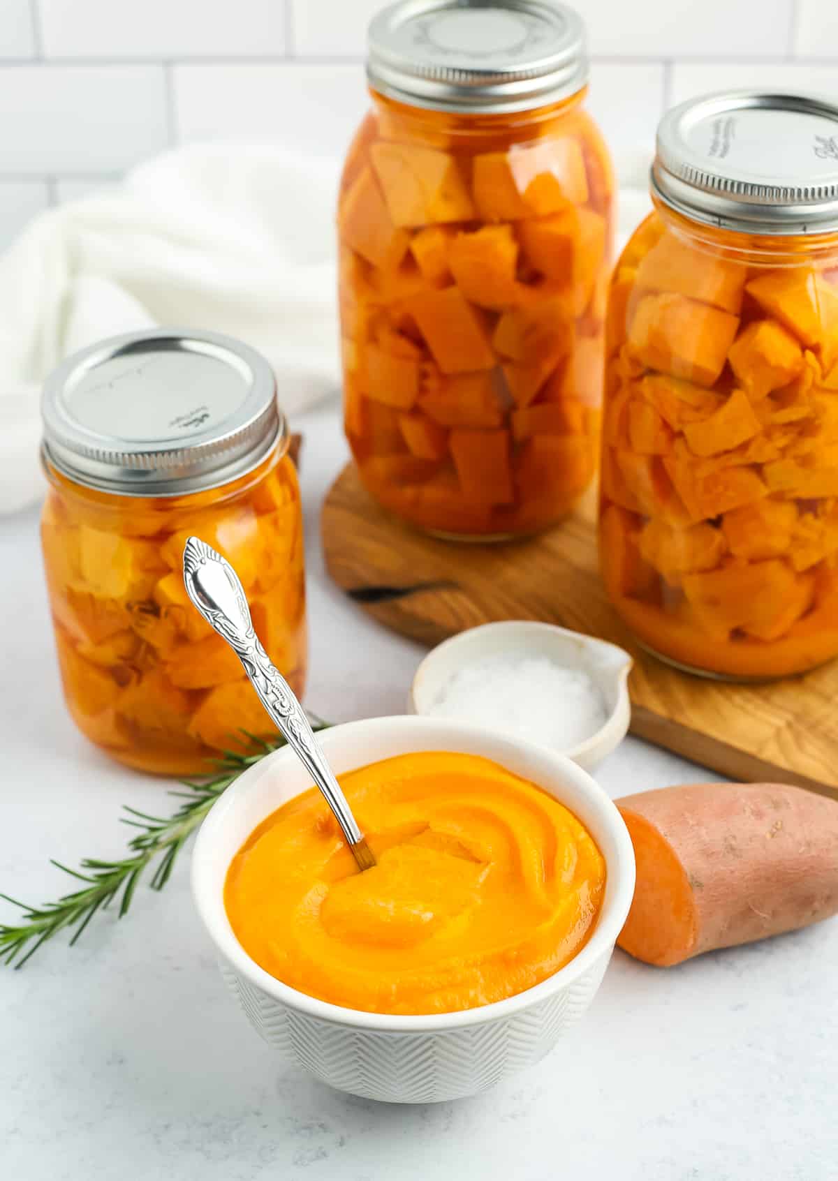 a bowl of sweet potato mash with jars in the background.