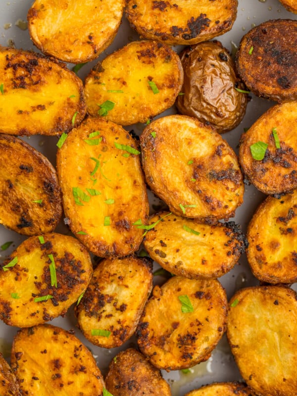 Roasted garlic potatoes on a baking sheet topped with chopped parsley.