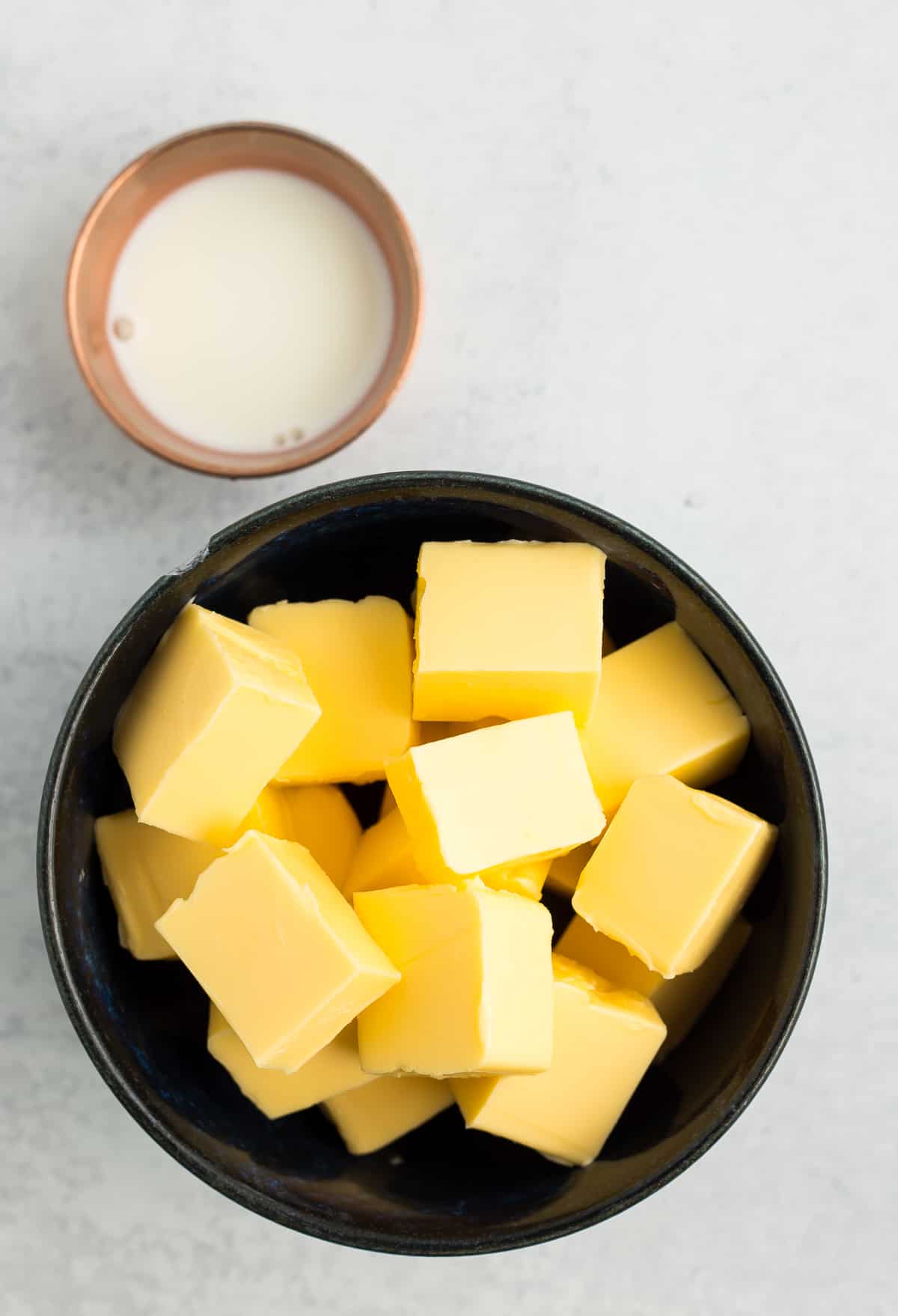 a dark blue bowl with cubes of butter, and a small bowl of milk.