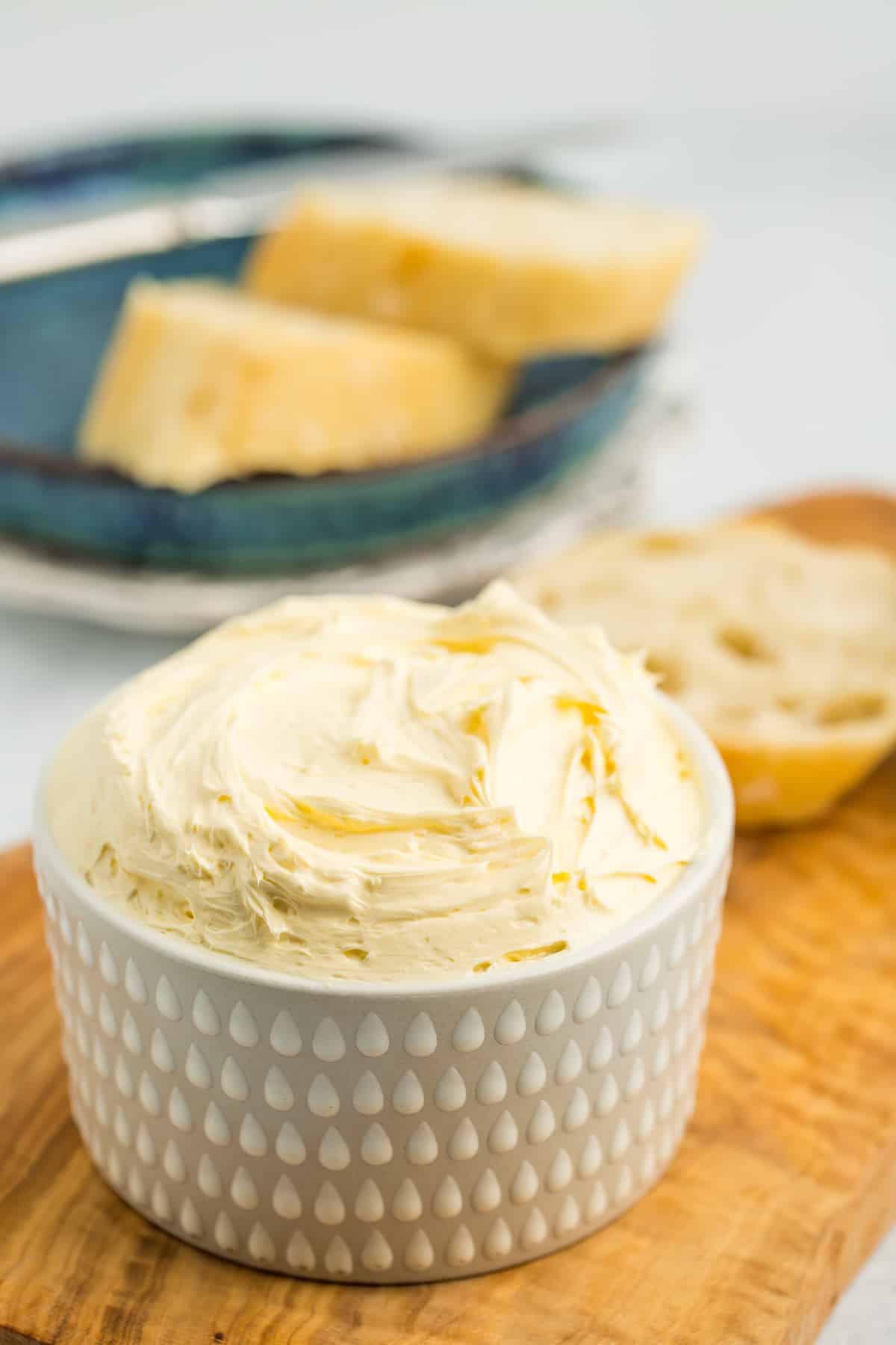 whipped butter in a white dish on a wooden cutting board.