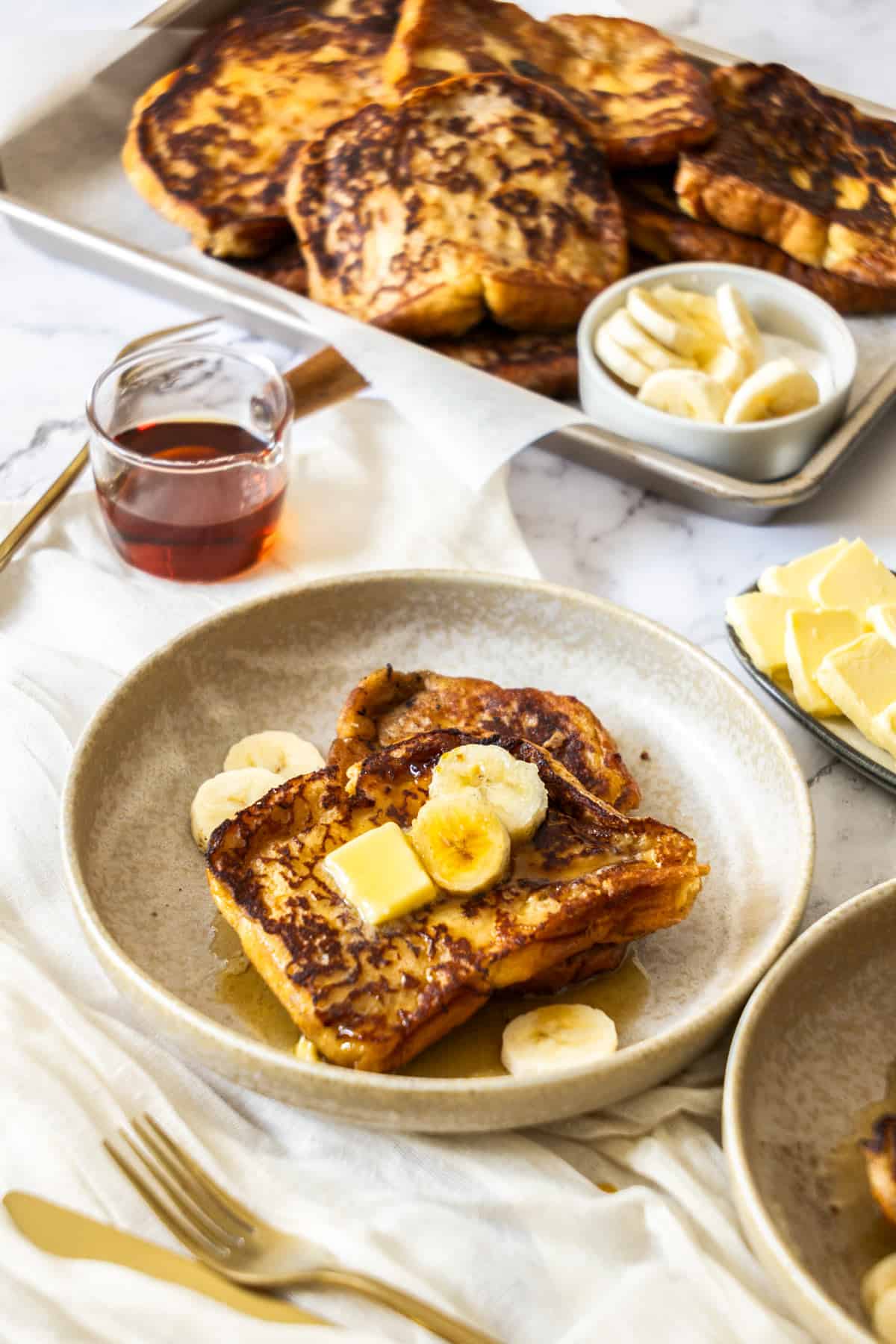 a plate of banana french toast topped with sliced bananas and syrup.