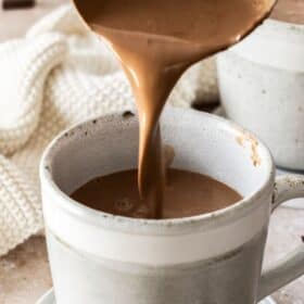 a ladle of hot chocolate being poured into a mug.