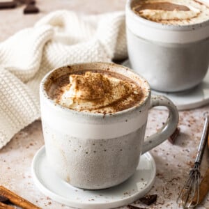2 mugs of crockpot hot chocolate on saucers.