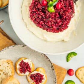 a white bowl with cranberry jalapeño dip with crackers and dip on a plate.