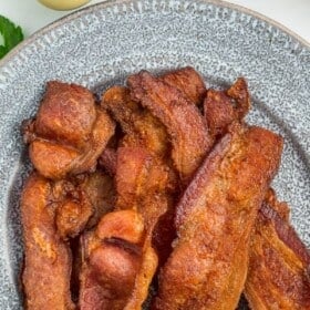 cooked bacon on a grey plate.