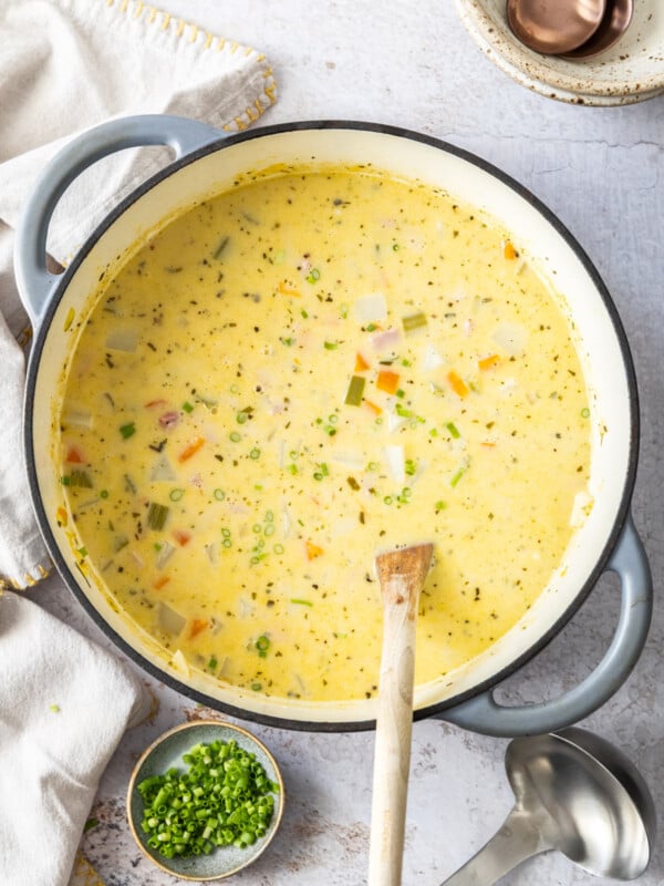 a large stockpot of ham and potato soup with a wooden spoon in it.