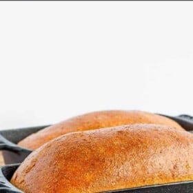 two loaves of honey wheat bread in cast iron bread pans.