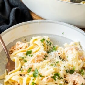 a grey and white bowl of creamy pasta topped with lox.