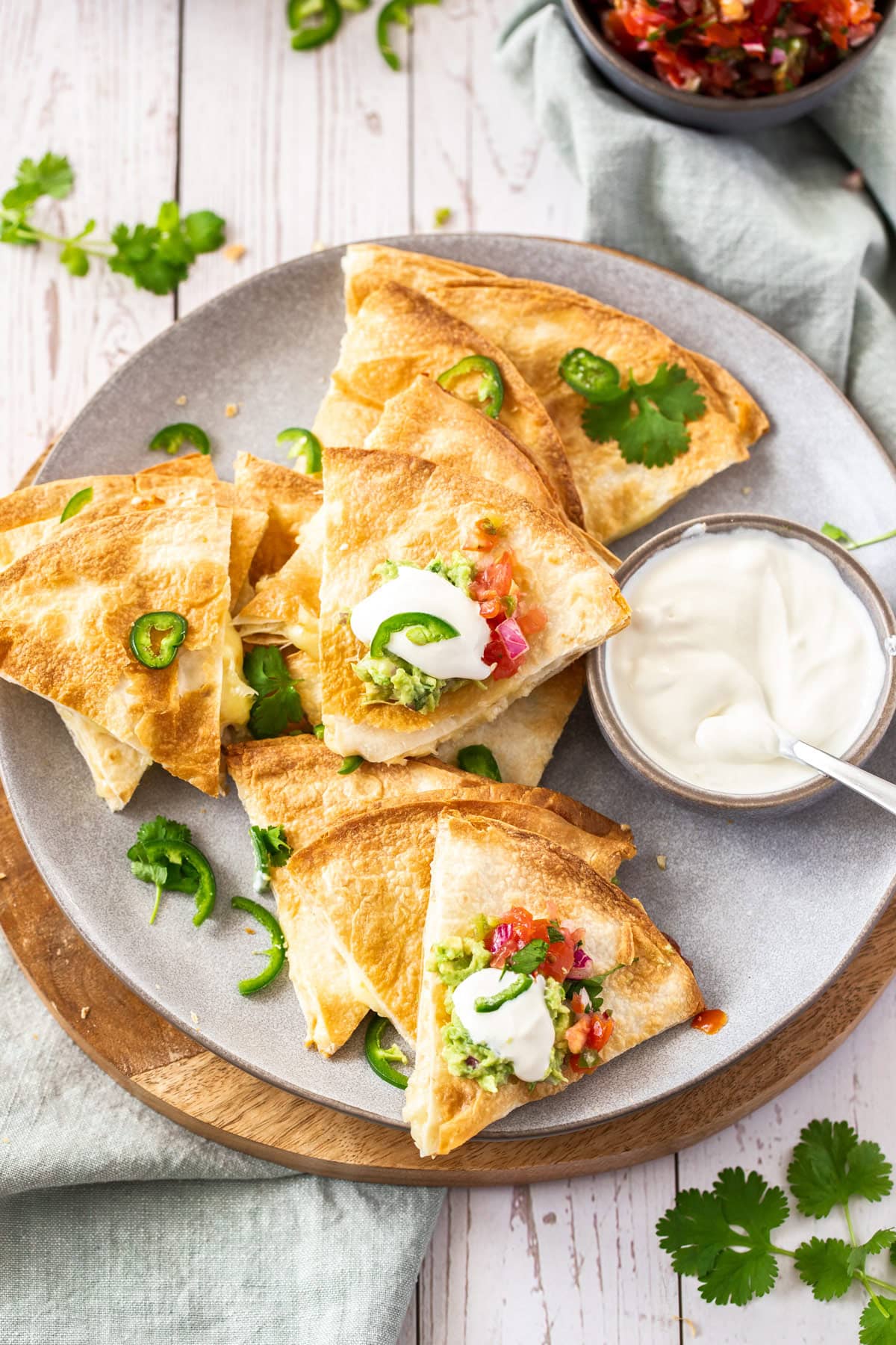 a plate of air fryer quicke quesadillas topped with sour cream, cilantro, and jalapeños.