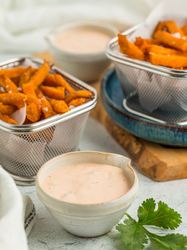 two bins of sweet potato fries and two small bowls with dipping sauce.