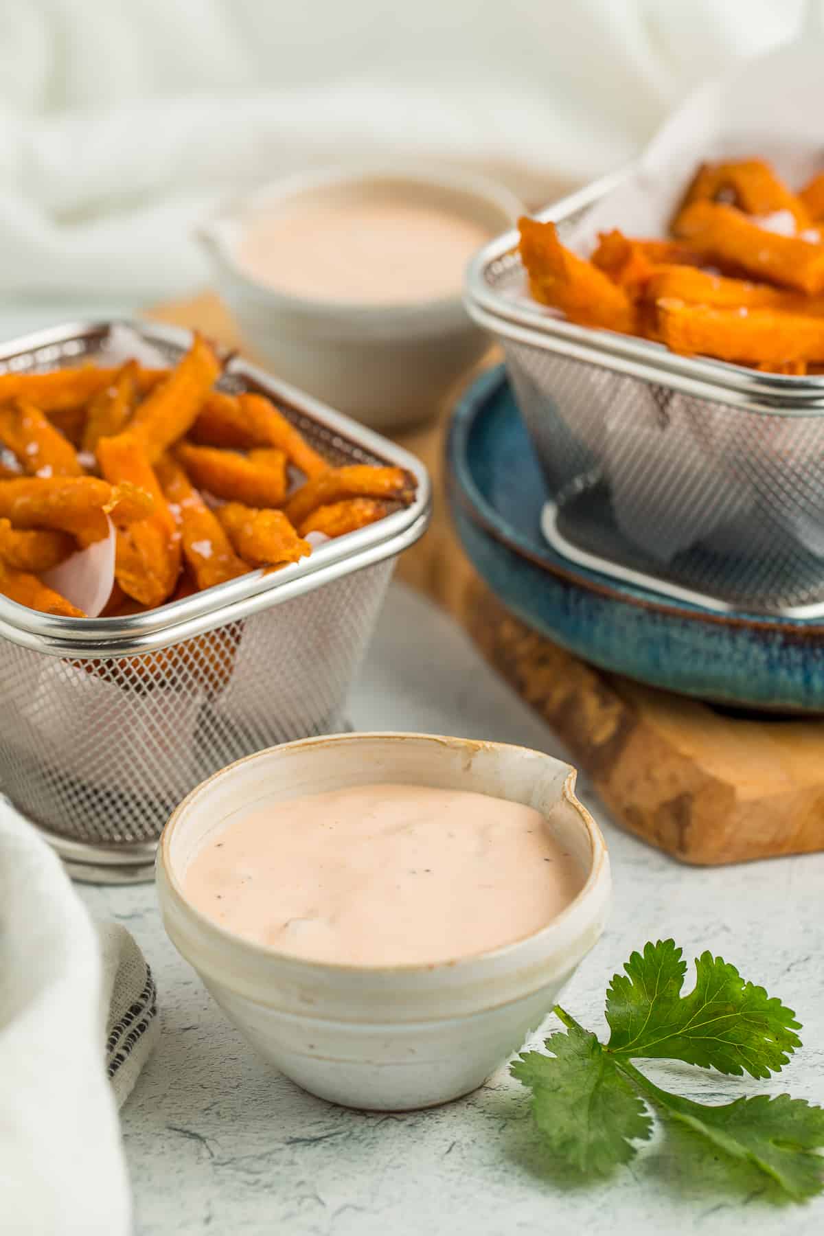 two bins of sweet potato fries and two small bowls with dipping sauce.