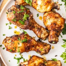 Air fryer chicken drumsticks on a plate topped with chopped parsley.