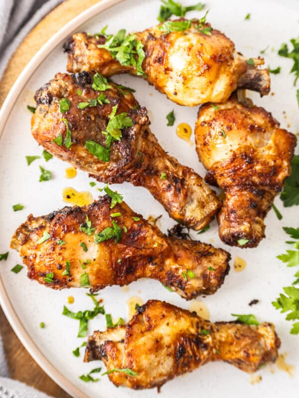 Air fryer chicken drumsticks on a plate topped with chopped parsley.