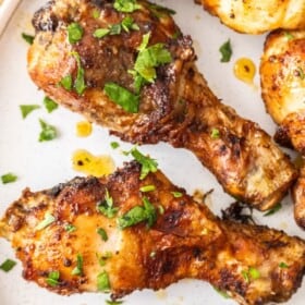 Air fryer chicken drumsticks on a plate topped with chopped parsley.