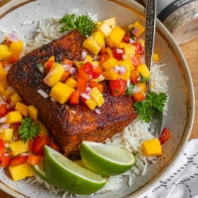 a plate with a piece of blackened mahi mahi topped with mango salsa.