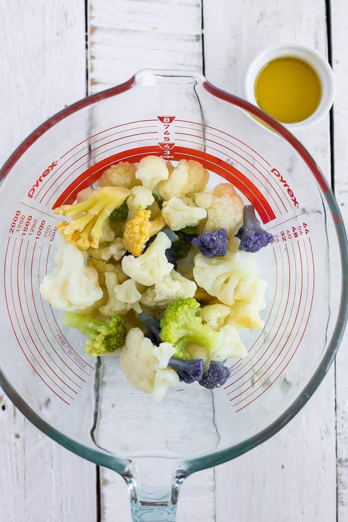 A glass bowl with chopped cauliflower and a small bowl of olive oil.