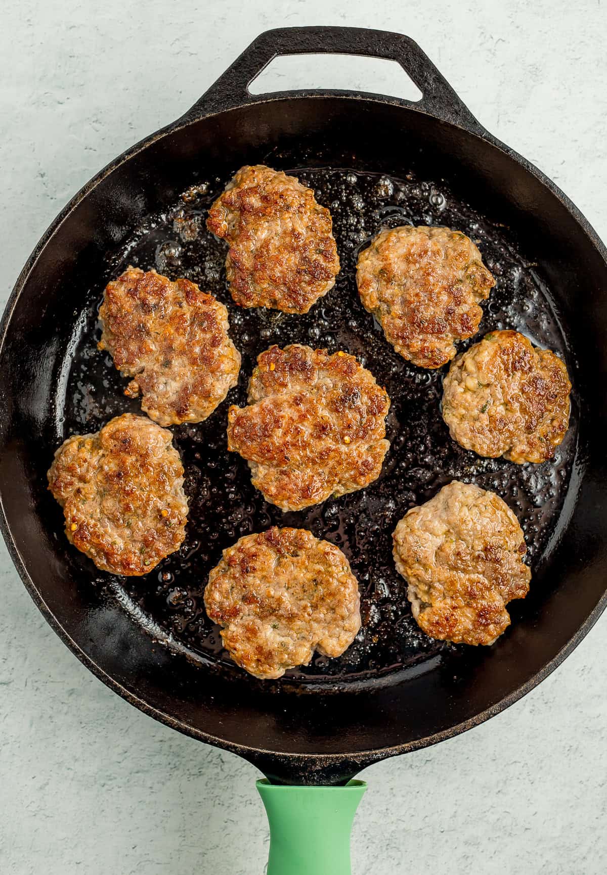 a cast iron skillet with brown sausage patties.