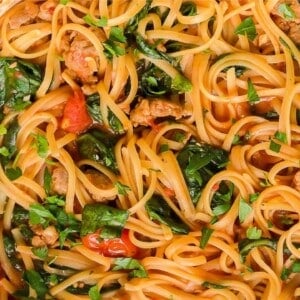 noodles, spinach, and sausage in a dish.